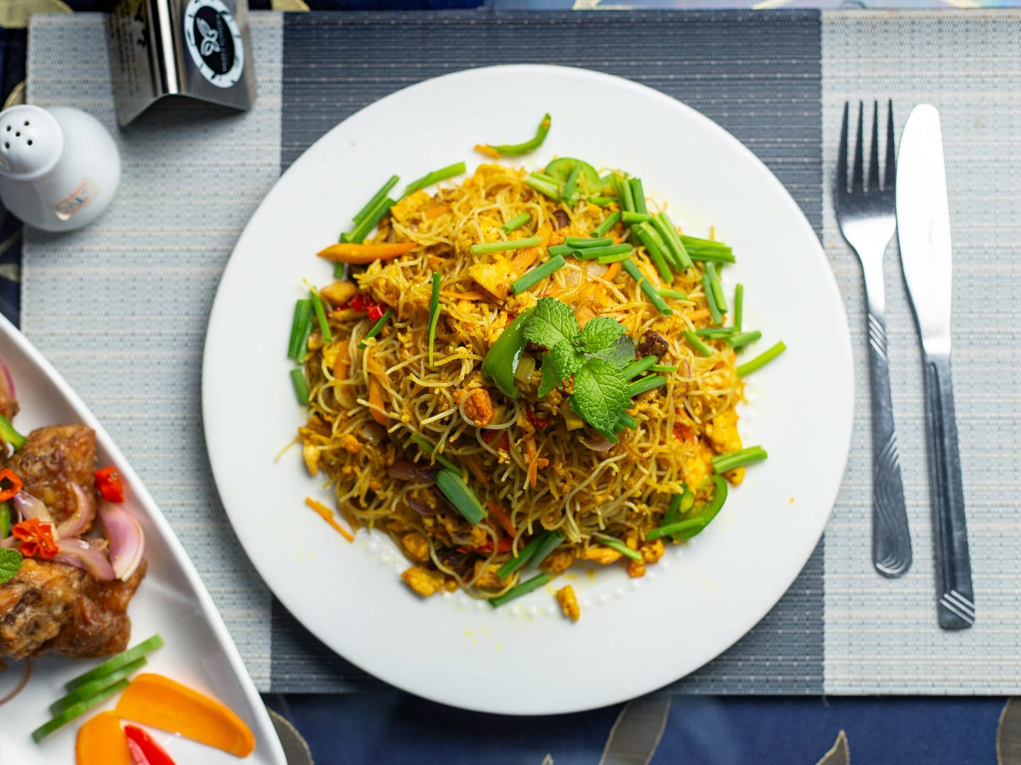 a white plate topped with food next to a fork and knife