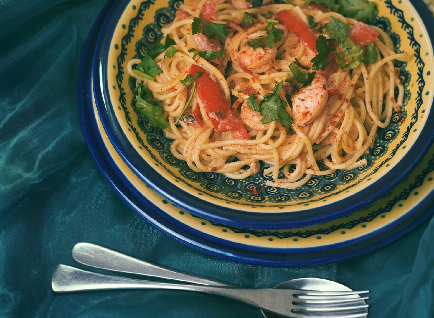 a plate of pasta with shrimp and tomatoes