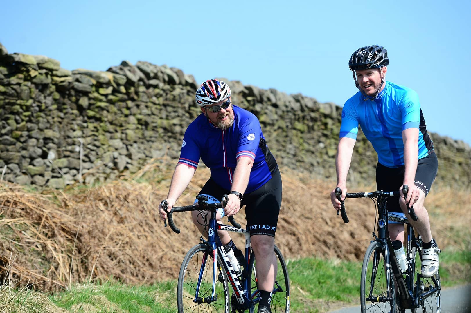 a couple of men riding bikes down a road